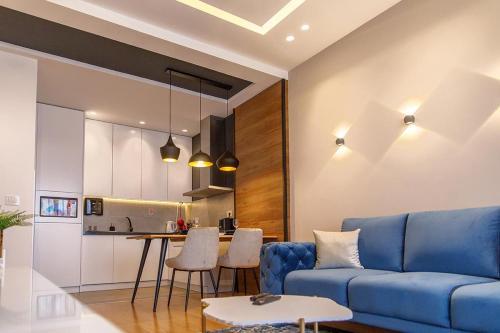 a living room with a blue couch and a kitchen at Dali Apartments Pupin Palace in Novi Sad