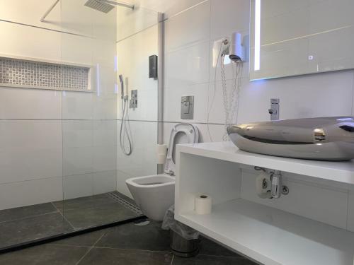 a white bathroom with a sink and a toilet at Aparthotel Praiano in Praia