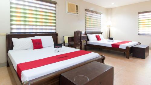 a hotel room with two beds and a table at RedDoorz at Teofila Lodge in Vigan
