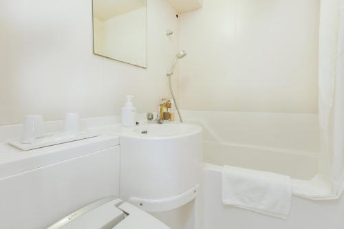 a white bathroom with a sink and a mirror at HOTEL MYSTAYS Otemae in Osaka