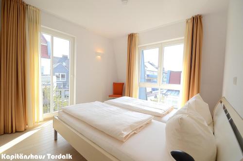 a bedroom with two beds and a large window at Kapitänshaus Tordalk mit 3 Schlafzimmern in Norderney