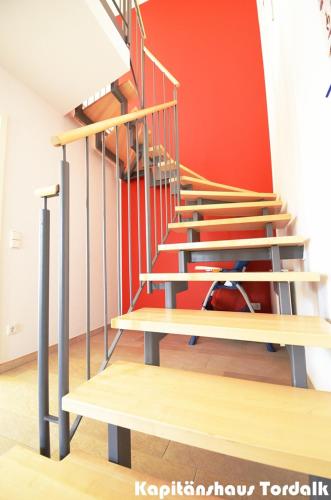 a set of stairs in a room with a red wall at Kapitänshaus Tordalk mit 3 Schlafzimmern in Norderney