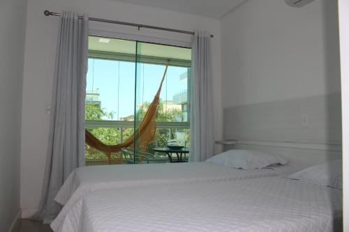a bedroom with a bed and a large window at Praia de Mariscal a 50 metros do mar in Bombinhas