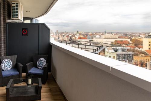 a balcony with chairs and a view of a city at Dali Apartments Pupin Palace in Novi Sad