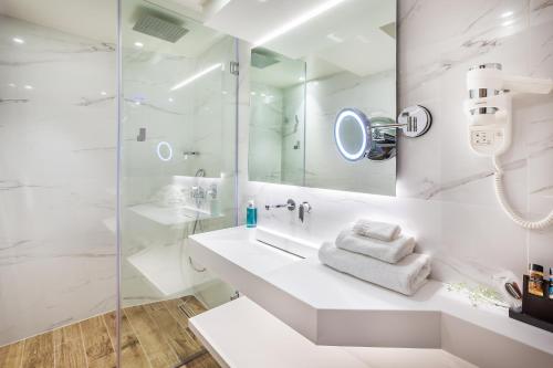a white bathroom with a sink and a shower at Imperial Plus Urban Smart Hotel Thessaloniki in Thessaloniki
