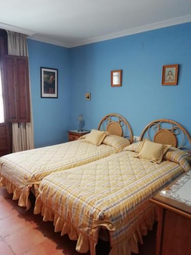 two beds in a bedroom with blue walls at La Noguera de Baena in Baena