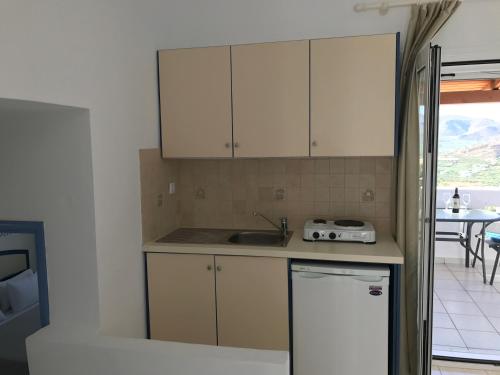 a kitchen with white cabinets and a sink at Castri Village Hotel in Palekastron