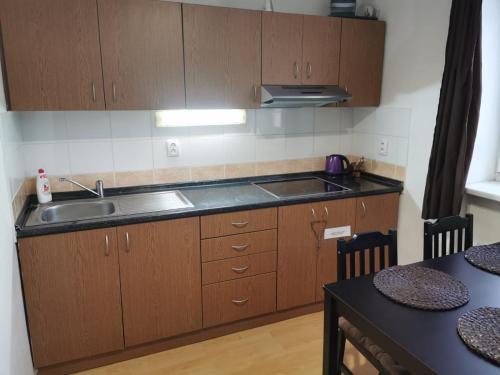 - une cuisine avec des placards en bois, un évier et une table dans l'établissement Apartmán Romance, à Lipno nad Vltavou