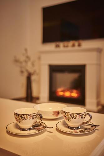 two tea cups and plates on a table with a fireplace at Apartment Breithorn - Charming home - free parking & Wifi in Lauterbrunnen