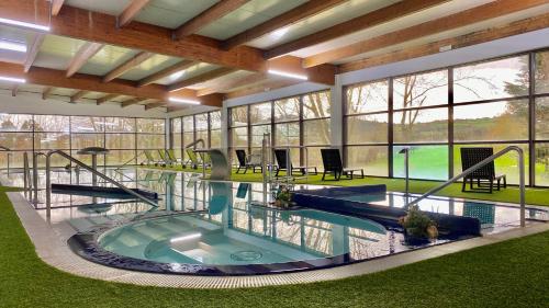 a large indoor swimming pool in a building with windows at Oca Palacio De La Llorea Hotel & Spa in Deva