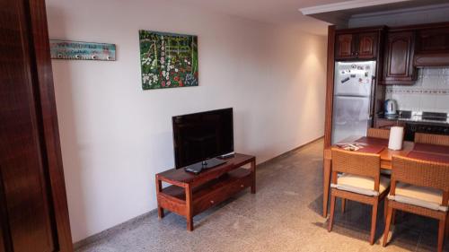a kitchen with a table and a tv and a table and a refrigerator at Playa Chica apartment in Puerto del Carmen