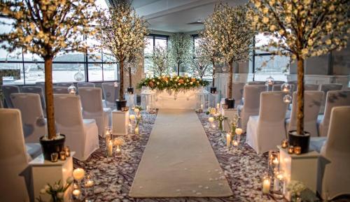 a wedding aisle with chairs and trees and candles at The Quay Hotel and Spa in Conwy