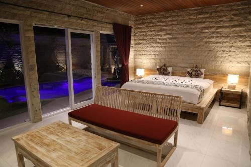 ein Schlafzimmer mit einem Bett und einer Bank in einem Zimmer in der Unterkunft Villa Latour in Seminyak