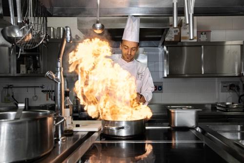 a chef cooking food in a pot in a kitchen at Hotel Garden in Moena