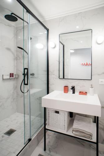 une salle de bain blanche avec un lavabo et une douche dans l'établissement SUITE GIDE : au cœur de la Rive Gauche, neuf, design, 2/4 personnes, à Paris