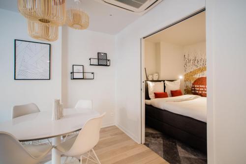- une chambre avec un lit, une table blanche et des chaises dans l'établissement SUITE GIDE : au cœur de la Rive Gauche, neuf, design, 2/4 personnes, à Paris