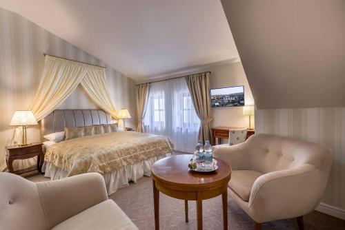 1 Schlafzimmer mit einem Bett, 2 Stühlen und einem Tisch in der Unterkunft Hotel Hoffmeister in Prag