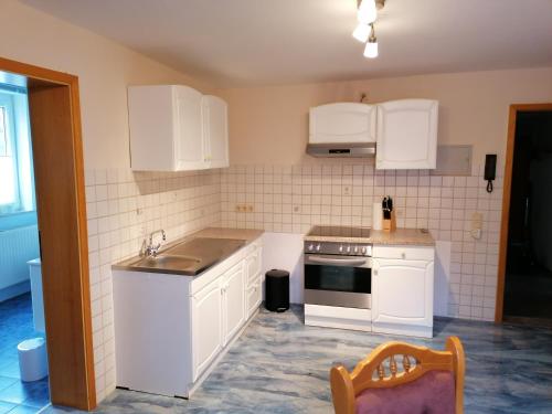 a kitchen with white cabinets and a sink at Ferienwohnungen Untermühle, Rothenbergerstr. 12 in Altenau