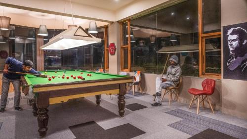 two men playing pool in a room with a pool table at Zostel Plus Bir in Bīr