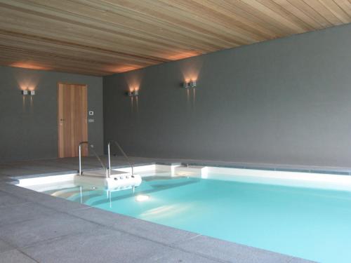 a swimming pool in a room with a wooden ceiling at Beautiful farmhouse in Beernem with big garden in Beernem