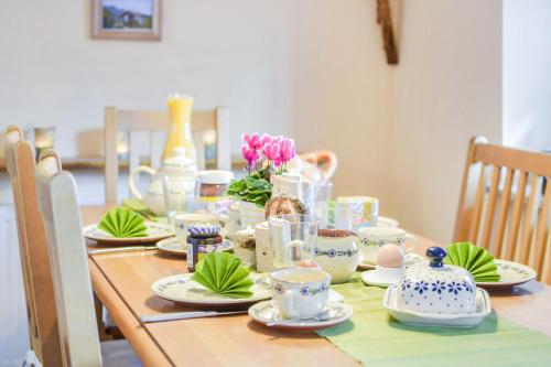a table with china dishes and flowers on it at Beim Kreuzfelder Zwiesel in Inzell