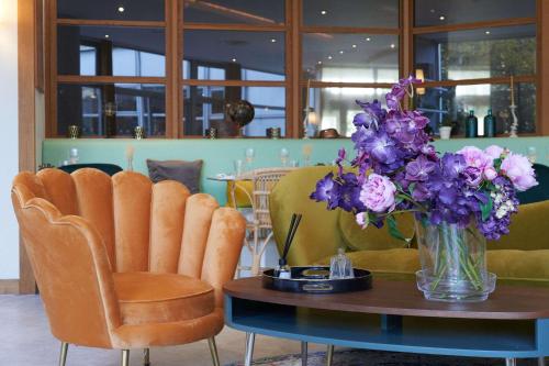 a table with a vase of purple flowers and chairs at Best Western Plus Paris Saclay in Saclay