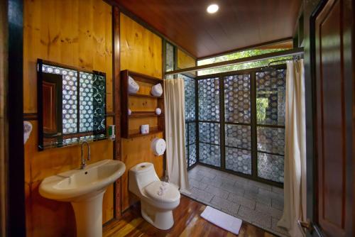 uma casa de banho com um lavatório, um WC e uma janela. em Hotel Heliconias Nature Inn & Hot Springs em Fortuna