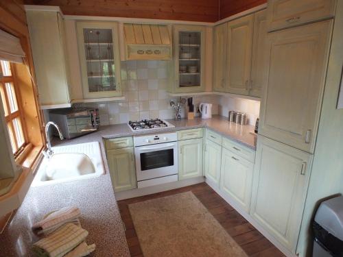 a kitchen with white cabinets and a sink and a stove at Oaks Log Cabins in Swanage