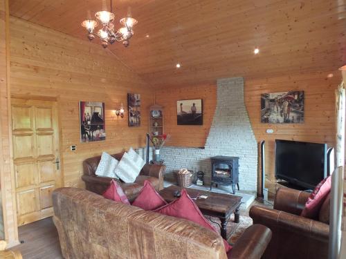 a living room with leather furniture and a fireplace at Oaks Log Cabins in Swanage