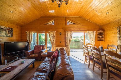 een woonkamer met een bank en een tv bij Oaks Log Cabins in Swanage