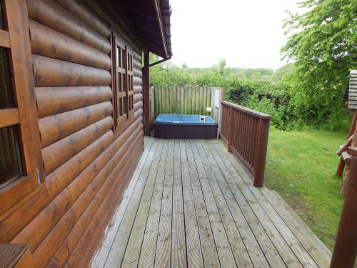 a wooden deck with a hot tub on the side of a house at Oaks Log Cabins in Swanage