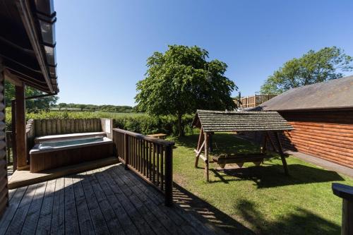 a deck with a hot tub and a swing at Oaks Log Cabins in Swanage