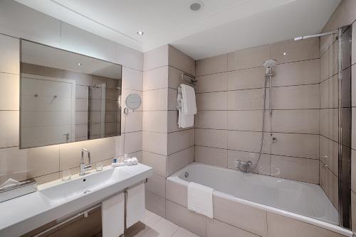 a bathroom with a tub and a sink and a mirror at Radisson Blu Hotel Milan in Milan