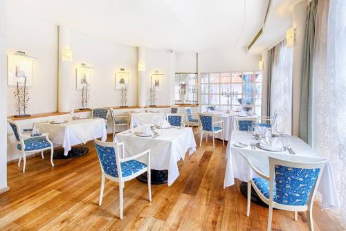 una sala da pranzo con tavoli bianchi e sedie blu di Hotel Hoffmeister a Praga