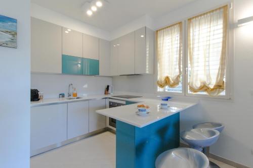 una cocina con armarios blancos y una isla azul en Il molo, en Finale Ligure