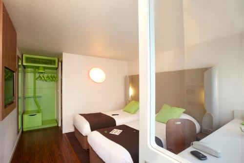 a hotel room with two beds and a green door at Campanile Chartres in Chartres