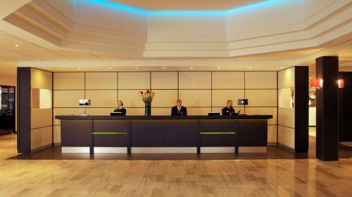 three people sitting at a reception desk in a lobby at Park Plaza Eindhoven in Eindhoven