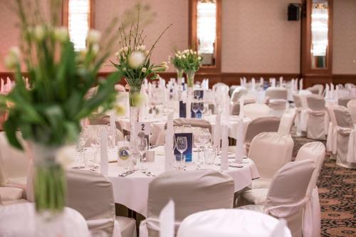 a room filled with white tables and chairs with vases at Radisson Blu Hotel Cottbus in Cottbus