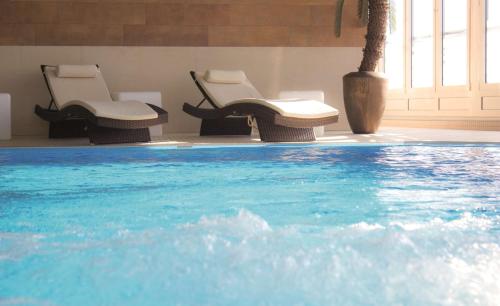 two chairs and a swimming pool in a building at Radisson Blu Hotel Cottbus in Cottbus