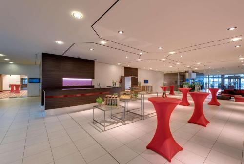 a lobby with red stools and a flat screen tv at Radisson Blu Hotel Leipzig in Leipzig