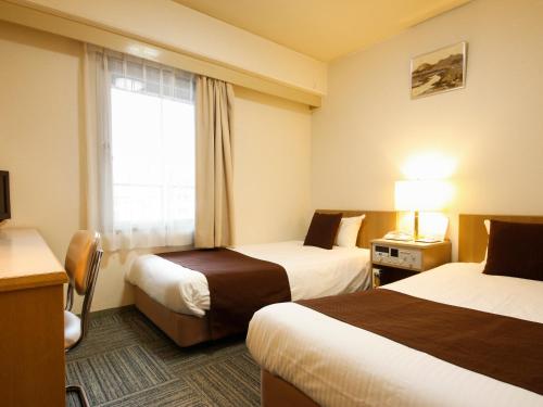 a hotel room with two beds and a window at Shin-Osaka Sunny Stone Hotel in Osaka