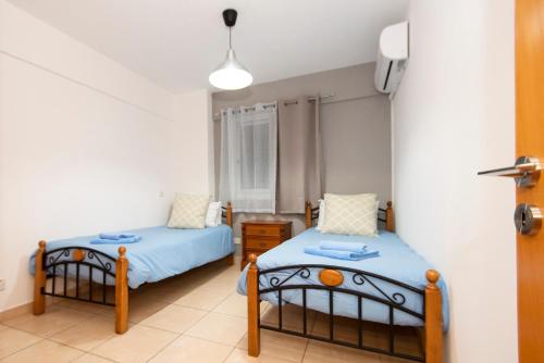 a bedroom with two beds with blue sheets at Olympia flat 201 in Larnaca