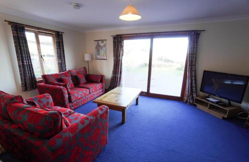 uma sala de estar com dois sofás vermelhos e uma televisão em Hamish's Cottage em Tobermory