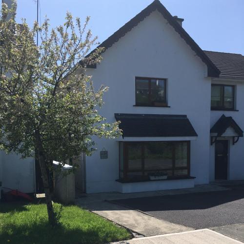 a white house with a tree in front of it at Beach Close Lodge in Kinsale