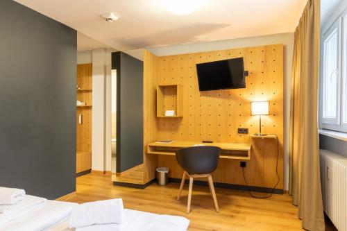 Habitación de hotel con escritorio y TV en la pared en mk hotel frankfurt en Frankfurt