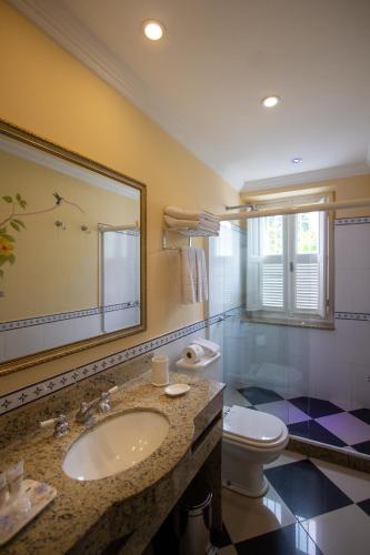 a bathroom with a sink and a toilet and a mirror at Hotel Solar do Império in Petrópolis
