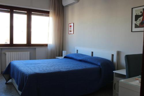 sypialnia z niebieskim łóżkiem i oknem w obiekcie San Vitale House w mieście Neapol
