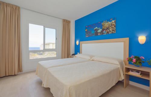 a bedroom with a large bed with a blue wall at Apartamentos Centro Cancajos in Los Cancajos