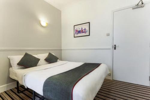 - une chambre avec un lit doté de draps et d'oreillers blancs dans l'établissement Enrico Hotel, à Londres