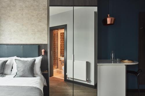 a bedroom with blue walls and a bed with a mirror at ARK Canary Wharf in London